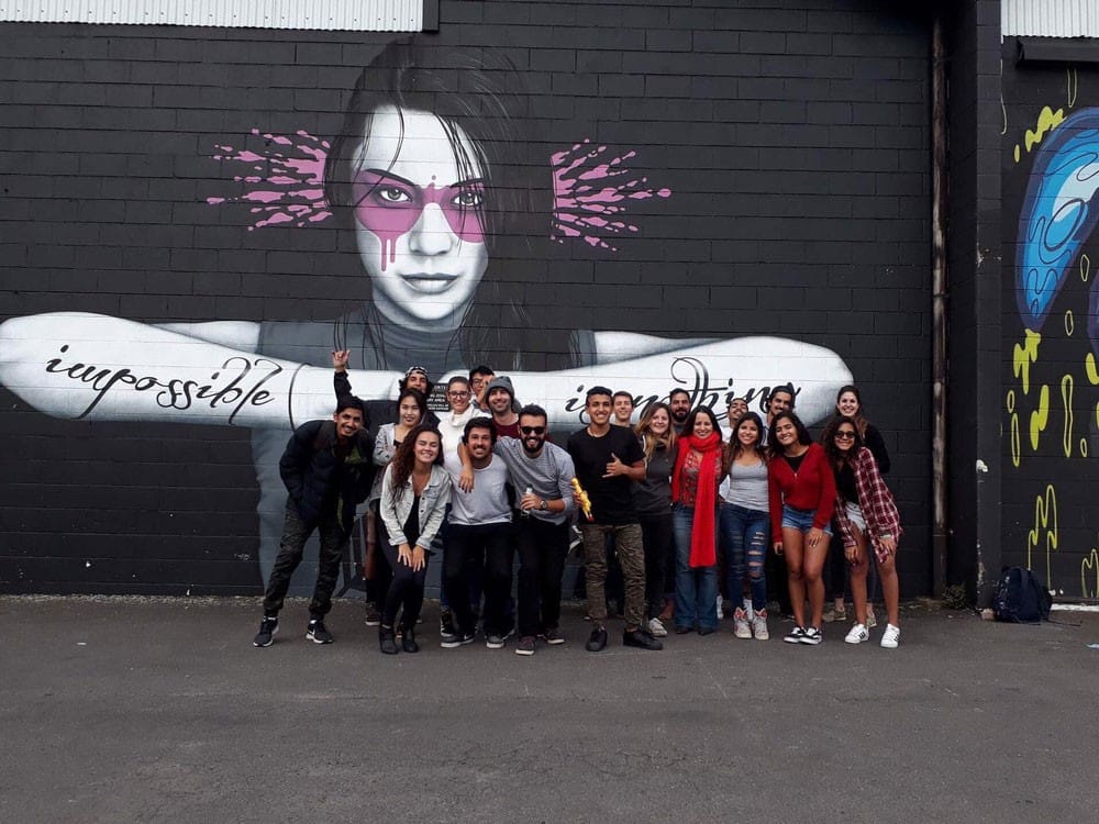 Vivir y trabajar en Nueva Zelanda grupo de amigos sonriendo para cámara y detrás una pared pintada